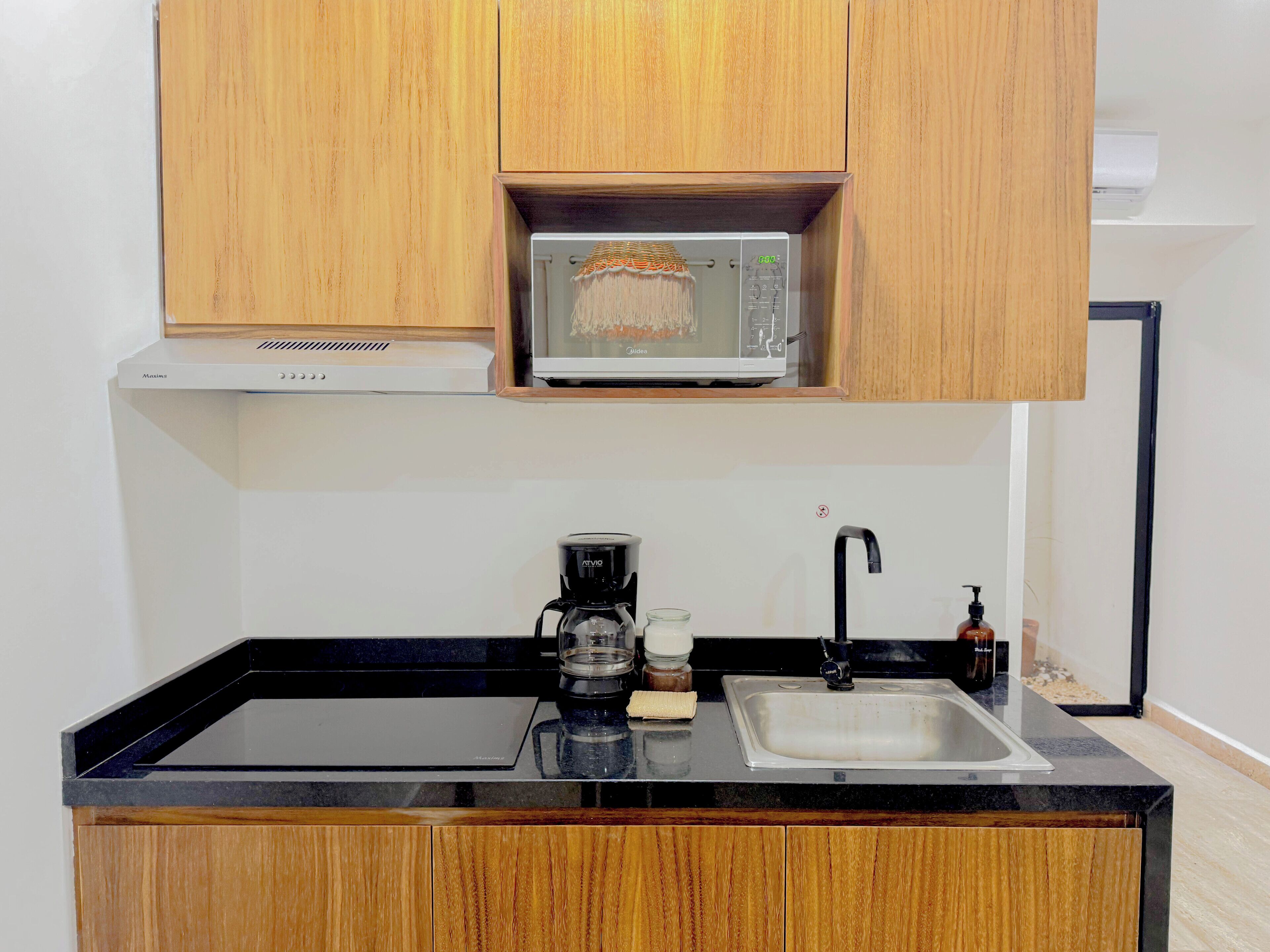 Cucina con mobili in legno, un forno a microonde, una macchina da caffè e un lavello.