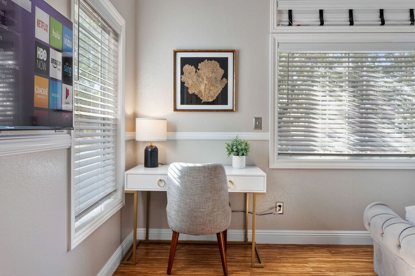 A room with a desk, chair, and a framed picture on the wall.