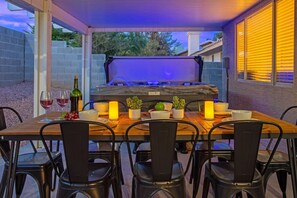 Een buiten eethoek met een tafel voor vier personen, omringd door stoelen, en een barbecuegrill op de achtergrond.