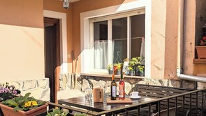 Un patio al aire libre con una mesa para dos, rodeado de plantas en macetas y una ventana con vistas.