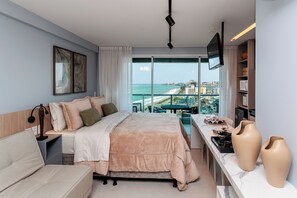 A modern hotel room with a large bed, a desk with a view, and a TV mounted on the wall. - RN Studio Premium 917 - Vista Mar (Maceió)