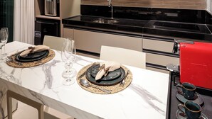 A modern kitchen with a flat-screen TV, built-in microwave, and red coffee machine. - RN Studio Premium 917 - Vista Mar (Maceió)