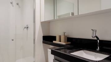 Enjoy a refreshing shower in the sleek bathroom with a glass-enclosed shower area, handheld showerhead, and modern sink.