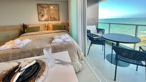 A hotel room with a bed, a balcony with a table and chairs, and a view of the ocean. - RN Studio Premium 917 - Vista Mar (Maceió)