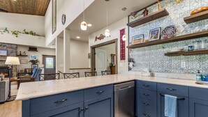 A modern kitchen with dark blue cabinets, a marble countertop, and a built-in dishwasher. - Hot tub, Mnt. Views, A/C, Downtown -  Eco Chalet! (Flagstaff)