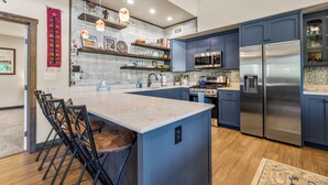 A modern kitchen with blue cabinets, a central island, and stainless steel appliances. - Hot tub, Mnt. Views, A/C, Downtown -  Eco Chalet! (Flagstaff)