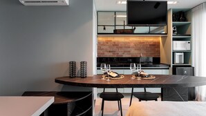 A modern kitchen with a brick backsplash, a flat-screen TV, and built-in appliances. - RN Studio Premium 918 - Vista Mar  (Maceió)