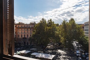 A street view with buildings, trees, and parked cars. - Manara 29 - FromHometoRome (Roma)
