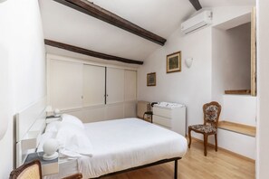 A bedroom with a bed, a chair, a dresser, and a radiator.