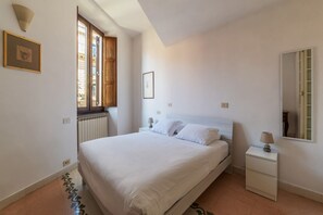 A bedroom with a bed, bedside tables, a window, and a mirror. - Manara 29 - FromHometoRome (Roma)