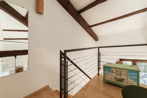 A wooden staircase with a metal railing, a green chest of drawers, and a large mirror on the wall. - Manara 29 - FromHometoRome (Roma)