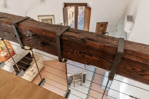 A wooden staircase with metal railings, a dining area with a table and chairs, and a view of the street below. - Manara 29 - FromHometoRome (Roma)