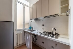 Una cocina compacta con estufa a gas, un lavamanos y una ventana.
