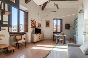 A spacious living area with a wooden staircase, a dining table, and a sofa. - Manara 29 - FromHometoRome (Roma)