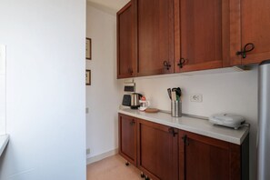 A kitchen with wooden cabinets, a countertop, a coffee maker, a kettle, a toaster, and a scale. - Manara 29 - FromHometoRome (Roma)