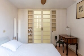 Un dormitorio con cama, escritorio, silla y armario con estantes.