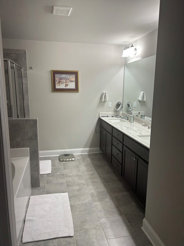 A modern bathroom with a large vanity, a shower, and a framed picture on the wall.