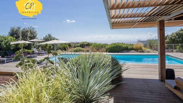 A poolside area with lounge chairs and umbrellas, a wooden deck, and a view of the pool. - Villa d’exception 4 chambres, piscine, vue mer (Porto-Vecchio)