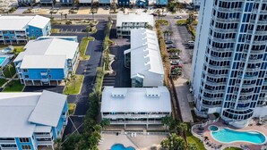 An aerial view of a coastal hotel with multiple buildings, a swimming pool, and a dock extending into the water.