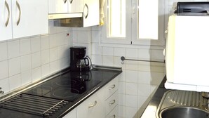 A kitchen with white cabinets, a black countertop, a coffee maker, a clock, and a toaster.