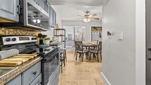 Une cuisine moderne équipée d’une cuisinière, d’un four et d’un four à micro-ondes. On y trouve également un coin repas avec une table et des chaises.