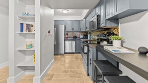 Une cuisine moderne avec des meubles gris, un réfrigérateur en acier inoxydable et un dosseret carrelé.