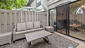 Une terrasse avec un canapé en osier, une petite table et un tapis à motifs.