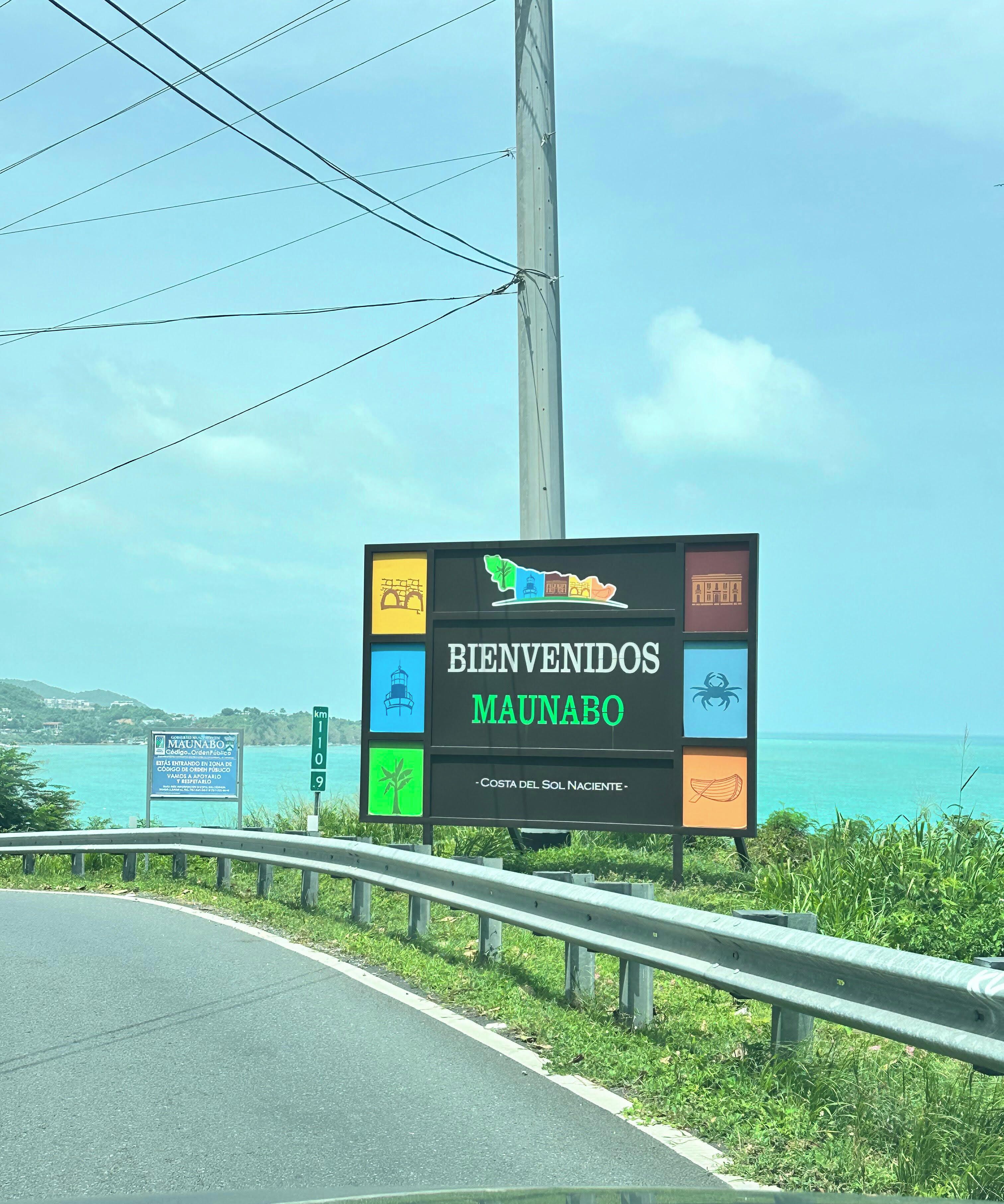 Letrero de bienvenida a Maunabo con iconos de puntos de referencia, un faro y una playa.