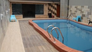 En inomhuspool med ett kaklat poolområde, en tegelvägg och en kaklad vägg med ett geometriskt mönster.