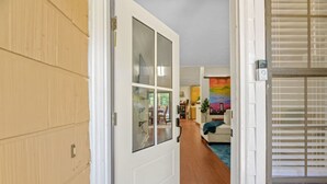 A hallway leading to a living room with a sofa and a painting. - Spacious 4BR Near FSU & A&M | BBQ, Deck, Game Room (Tallahassee)