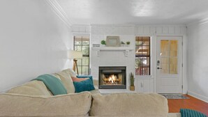 A living room with a fireplace, white walls, and a door with glass panels. - Spacious 4BR Near FSU & A&M | BBQ, Deck, Game Room (Tallahassee)