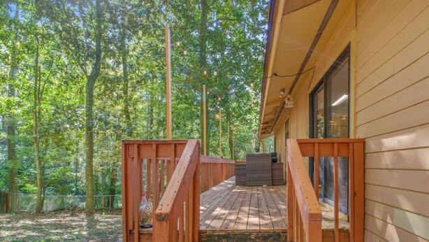 A wooden deck leading to a cabin with a glass door, surrounded by a forest. - Spacious 4BR Near FSU & A&M | BBQ, Deck, Game Room (Tallahassee)