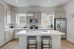 Una cocina moderna con una isla central, iluminación colgante y vistas al exterior.