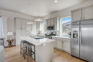 A modern kitchen with white cabinetry, stainless steel appliances, and a large island with bar stools.