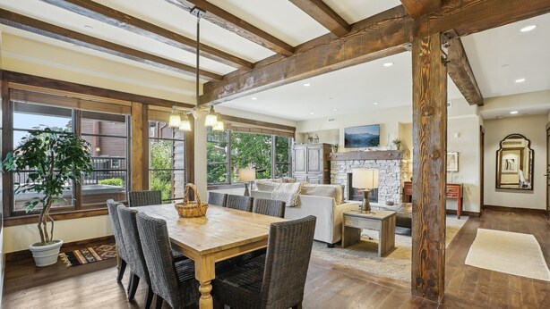 Un amplio espacio de sala con una mesa de comedor de madera, sillas de mimbre oscuro y un gran ventanal con vistas al exterior.