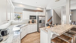 A modern kitchen with white cabinetry, stainless steel appliances, and a granite countertop.