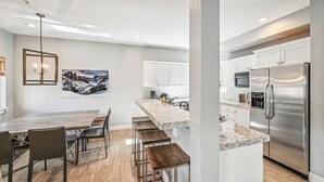 A modern kitchen with white cabinets, a stainless steel refrigerator, and a granite countertop.
