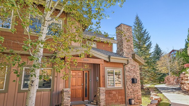 A two-story house with a brick chimney, a front door, and a small porch.