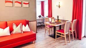 En moderne stue med en rød sofa, et spisebord med stole og røde gardiner.