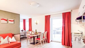En moderne stue med en rød sofa, et træspisebord og røde gardiner.