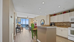 A modern kitchen with a central island, white cabinets, and a view to the outside. - Spanish Key 307 | Beachfront | Steps from Flora Bama | Pools | My Beach Getaways (Pensacola)