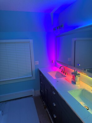 Ein Badezimmer mit blauer Wand, Waschbecken in Weiß und einem Spiegel.