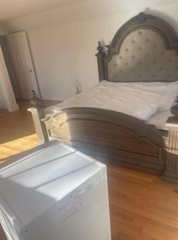 Ein Schlafzimmer mit einem hölzernen Bett, einem Nachttisch und einer weißen Kommode.
