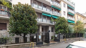 A multi-story residential building with balconies, a gated entrance, and a small tree in front. - GuestHost - Milan Gambara Balcony Apartment (Milano)