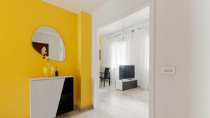 A modern interior with a yellow wall, a round mirror, a white cabinet, and a doorway leading to another room. - GuestHost - Milan Gambara Balcony Apartment (Milano)