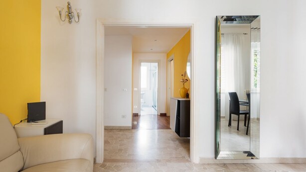 A hallway with a sofa, a desk, and a dining area with chairs and a table. - GuestHost - Milan Gambara Balcony Apartment (Milano)