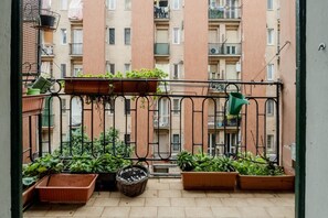 Un balcón con plantas en macetas y barandilla de metal.