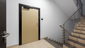 A modern interior with a beige door labeled "223," a metal staircase, and tiled flooring.