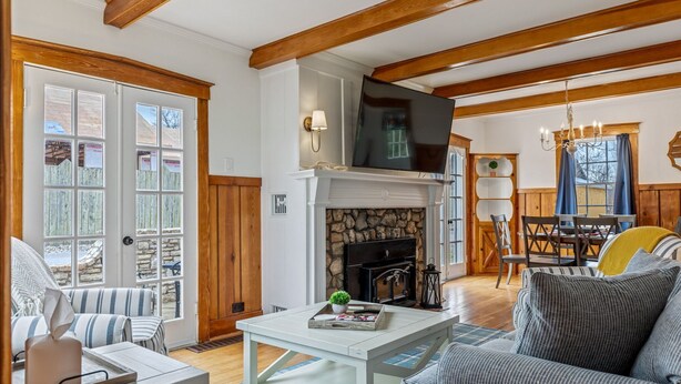 A living room with a fireplace, a television, and a dining area with wooden furniture. - Charming Blake Cottage | Augusta Wine Country (Augusta)