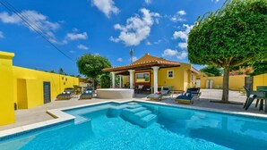 Una piscina con sillas de descanso y un área de patio techada.